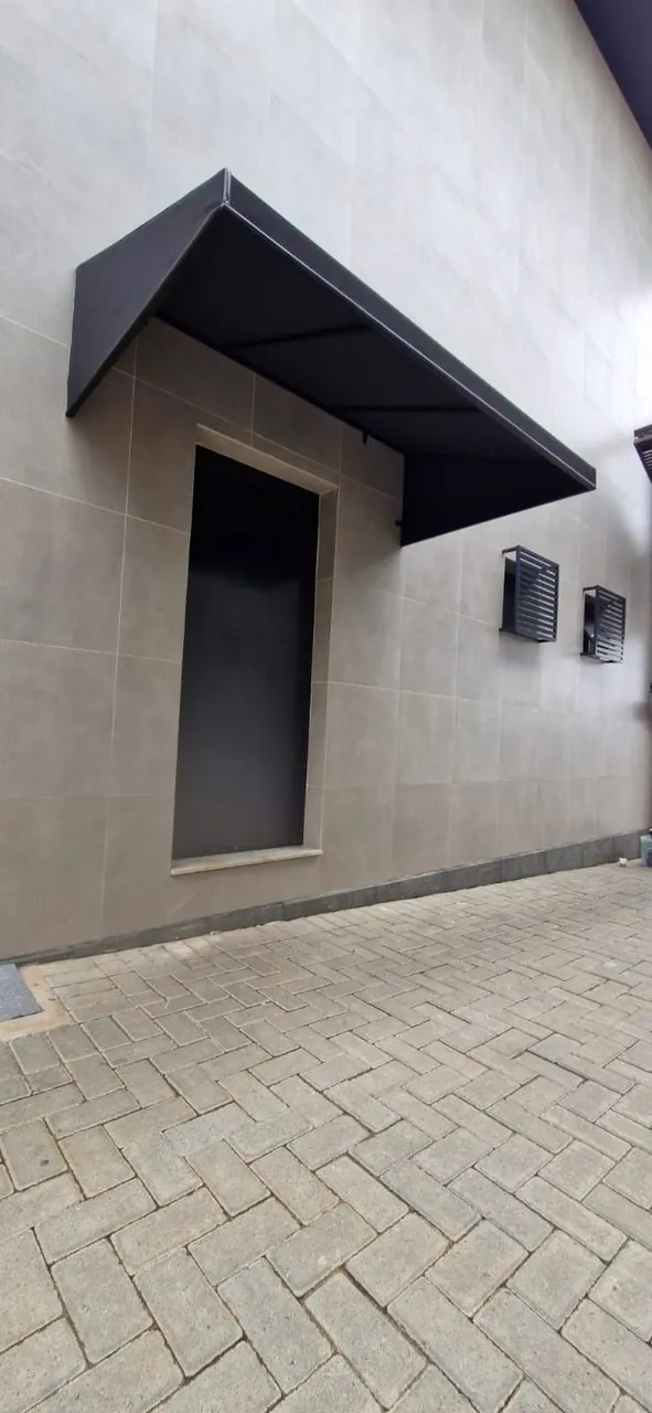 Toldo fixo preto moderno sobre porta, parede em porcelanato — FG Toldos Curitiba